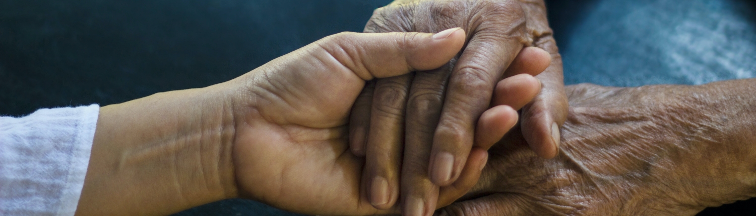 Daughter holding hand of mother elderly that is alzheimer and parkinson patient on dark background.