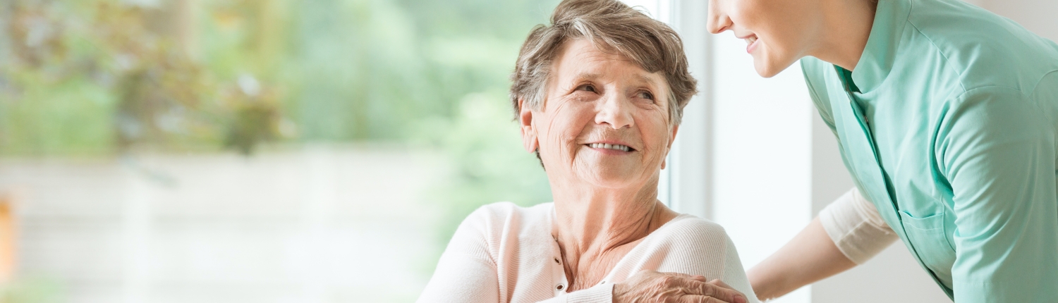 Young nurse helping an elderly woman in a wheelchair. Nursing home concept